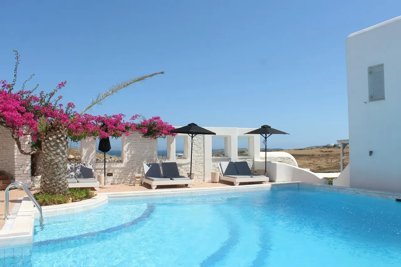 Terraza de un hotel mediterráneo con piscina, flores y arquitectura blanca